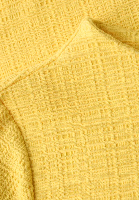 Nahaufnahme eines gelben, strukturierten Strickstoffs mit Waffelmuster.